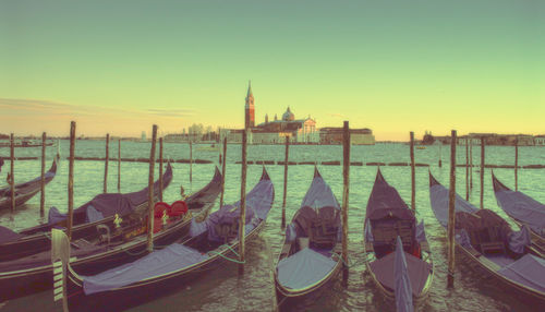Boats moored at canal against clear sky