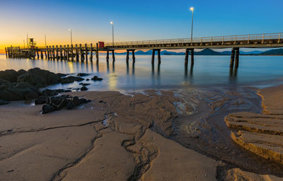 Pier on beach at dusk