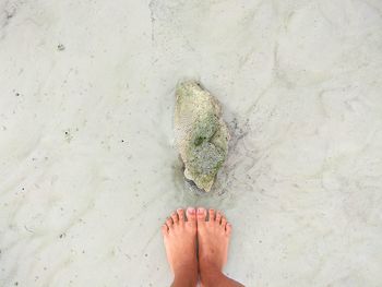 Low section of woman standing on sand at beach