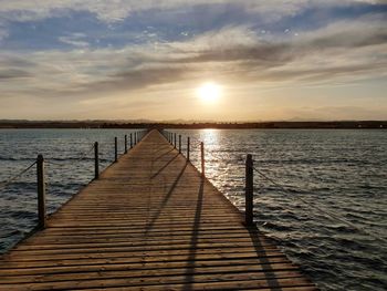 Pier over sea against sky during sunset