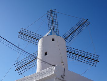 Low angle view of traditional windmill against clear blue sky