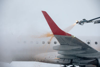 Deicing of airplane wing before flight. winter frosty day and ground service at airport.