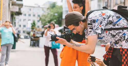 Young man photographing with mobile phone while standing on street