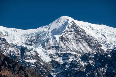 Scenic view of snowcapped mountains against clear blue sky