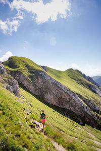 Rear view of man standing on mountain against sky