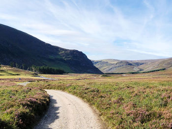 Road leading towards mountains against sky