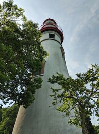 Low angle view of lighthouse by building against sky