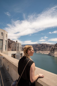 Woman standing by retaining wall against sky