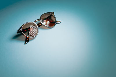 Close-up of sunglasses on table against blue background