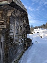 Built structure by frozen river against sky during winter