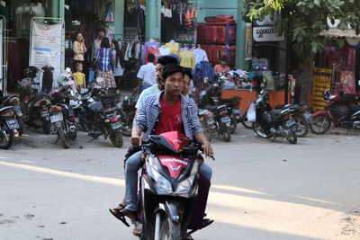 Full length of woman riding motor scooter on road