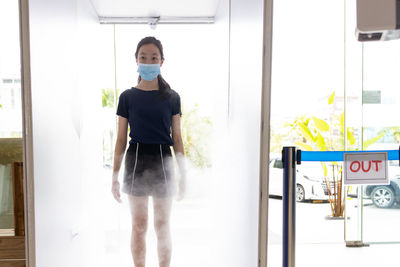 Portrait of young woman standing against door