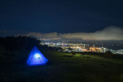 Illuminated tent on field against sky at night