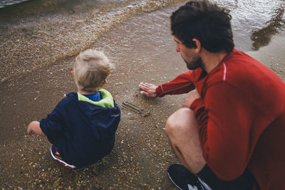 High angle view of father and son sitting at the beach