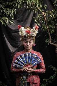 Portrait of woman wearing traditional clothing while standing against backdrop