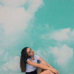 Young woman looking away against sky