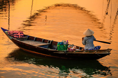 Woman in boat sailing on river during sunset