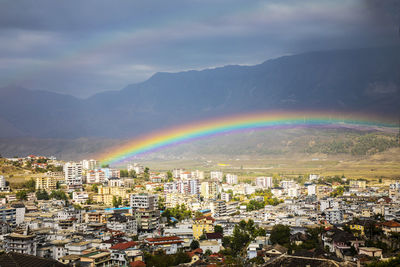 Rainbow over buildings in city against sky