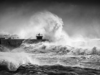 Waves splashing on shore against sky