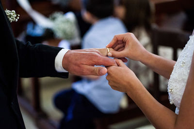 Midsection of couple putting wedding ring