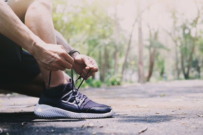 Low section of man tying shoelace on road