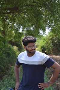 Portrait of young man standing against trees