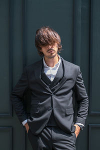 Portrait of young man standing against wall