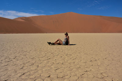 Man sitting on sand dune in desert