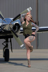 Young woman pinup model posing beside airplane propeller