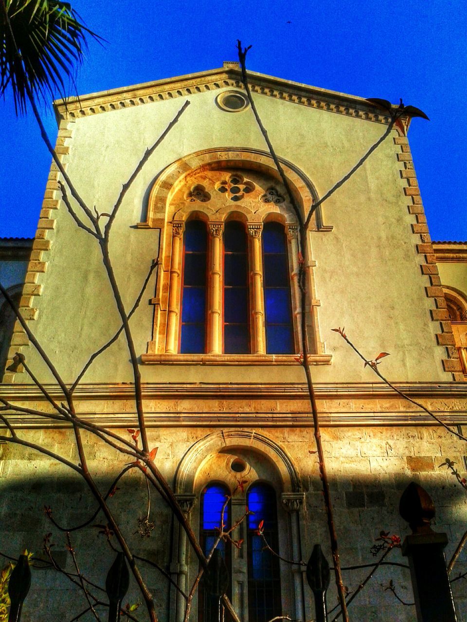 architecture, building exterior, church, low angle view, built structure, religion, place of worship, blue, spirituality, clear sky, cross, cathedral, arch, facade, window, sunlight, day, sky