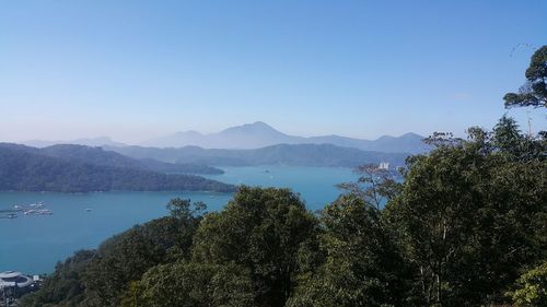 Scenic view of sea and mountains against clear blue sky