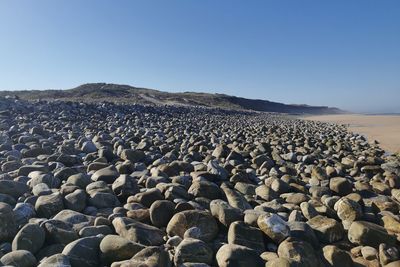 Rocks on beach against clear sky