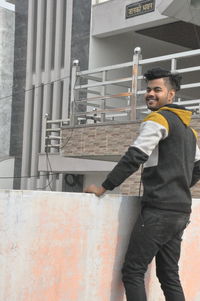Side view of young man standing against wall