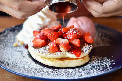 Cropped hand of person holding dessert in plate on table
