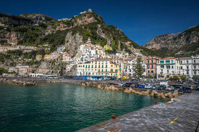 View of houses on mountain by sea against clear blue sky during sunny day