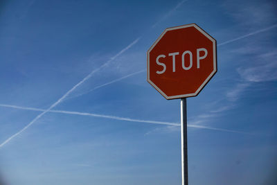 Low angle view of road sign against blue sky