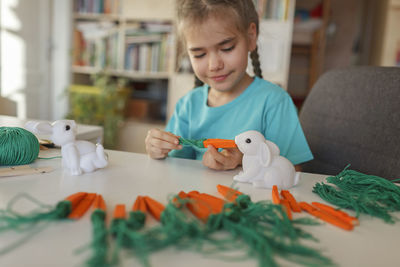 Cute girl doing craft while watching videos on laptop at home