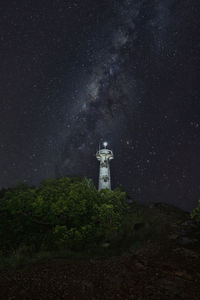 Lighthouse by sea against sky at night