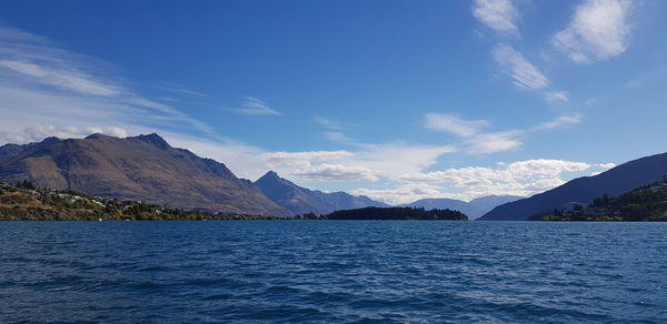 Scenic view of lake and mountains against blue sky