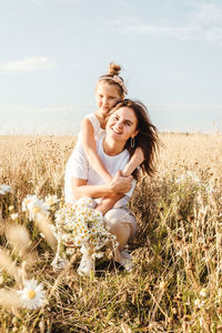 Portrait of smiling young woman on field against sky