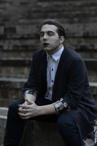 Thoughtful young man with eyes closed sitting on steps 