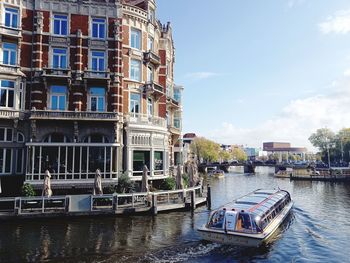 Boats in canal amidst buildings in city