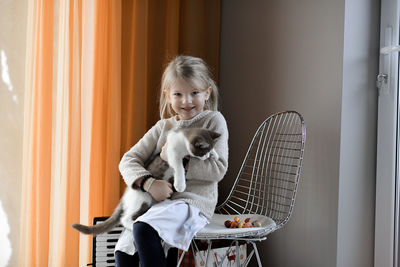 A cute little girl playing with a cat at home