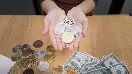 High angle view of hand holding coins on table