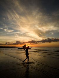 Silhouette man standing on beach against sky during sunset