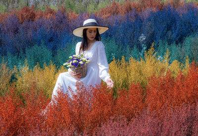 Woman wearing hat standing amidst multi colored plants