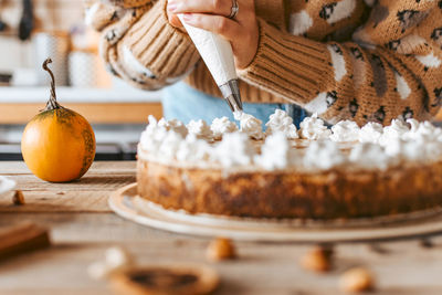 Close-up of woman baking cake. whipped cream, pumpkin pie.