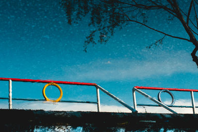 High angle view of tree and railing reflecting on lake