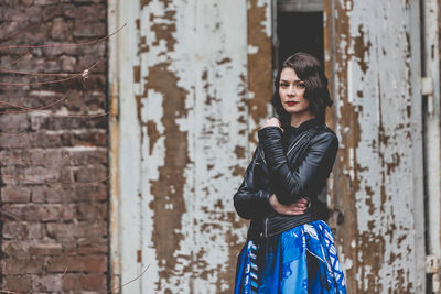 Portrait of woman standing against brick wall