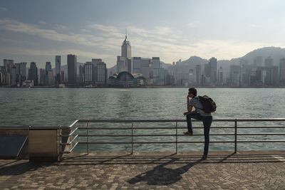 Man leaning on railing against buildings in city